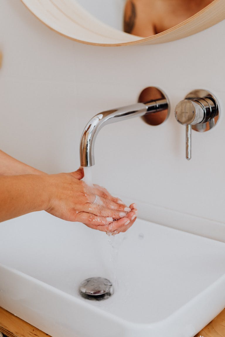 Person Cleaning Hands on Lavatory